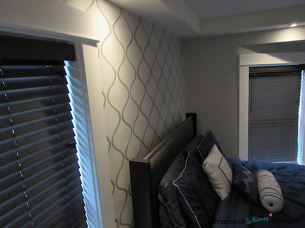 Master bedroom stenciled accent wall with master bed and windows.