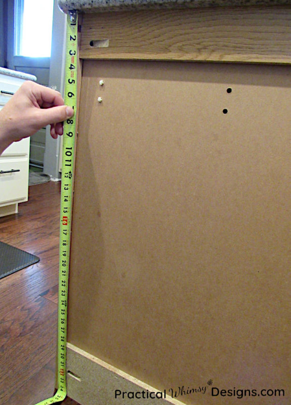 Measuring kitchen cabinet with tape measure