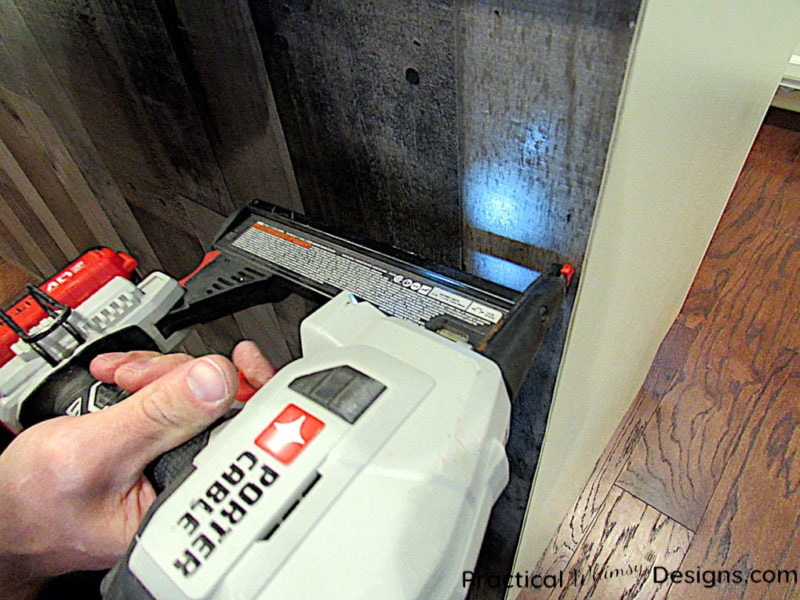 Using a trim nailer to nail paneling on cabinet