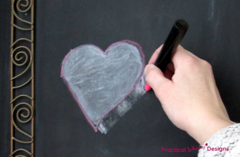 Hand outlining chalk heart with chalk marker