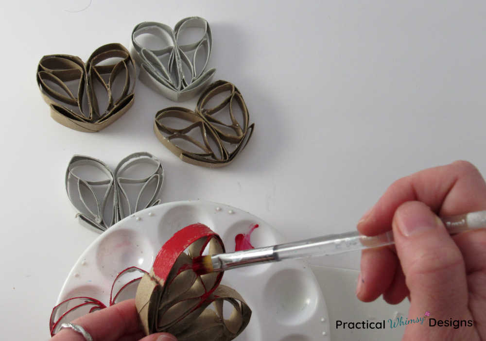 Painting 3D cardboard hearts red for DIY Valentines garland.