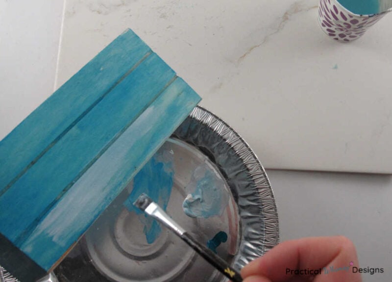 Painting white paint over blue on wooden box to create a white washed look