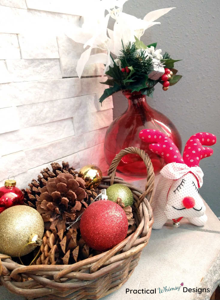 Basket of pinecones and ornaments, reindeer and flowers on hearth