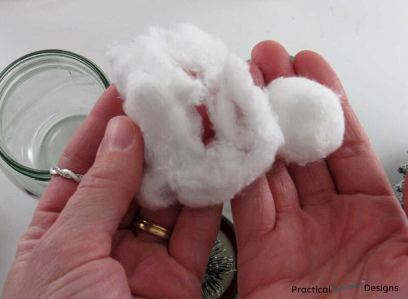 Cotton balls in hands, one ripped apart into snow, the other whole.