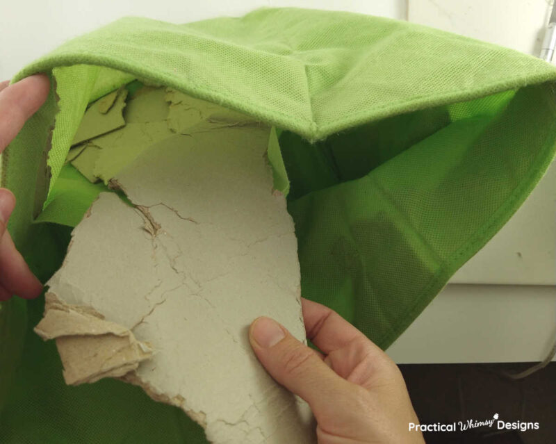Pulling crumpled paper out of green fabric storage cube.