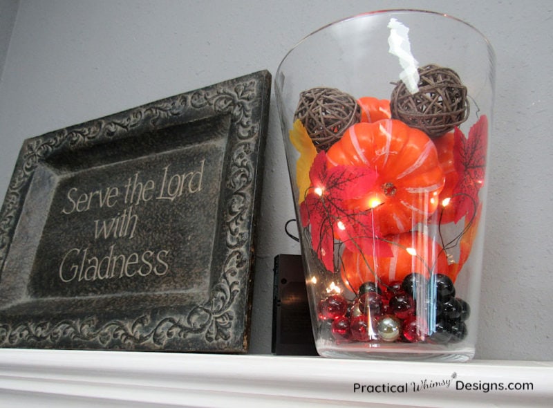 Pumpkins, lights, leaves, and marbles in a jar for an easy indoor fall decoration.