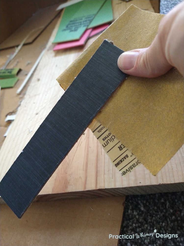 Sanding edge of faux book with sandpaper.