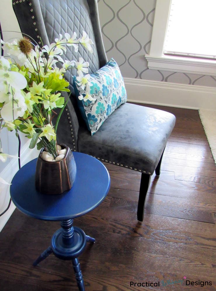 Blue spray painted side table makeover with flowers and vase next to chair.