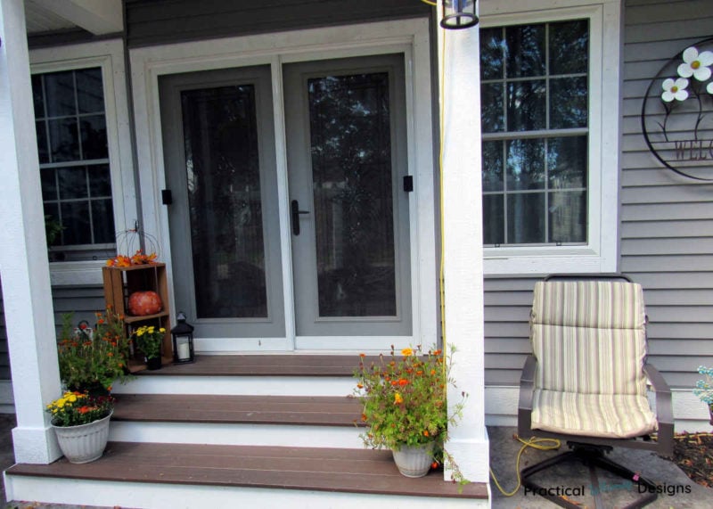 Small porch with fall decor of pumpkins and flowers