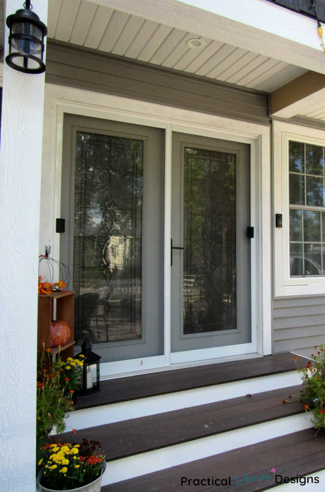 Small porch with fall decor and flowers on steps.