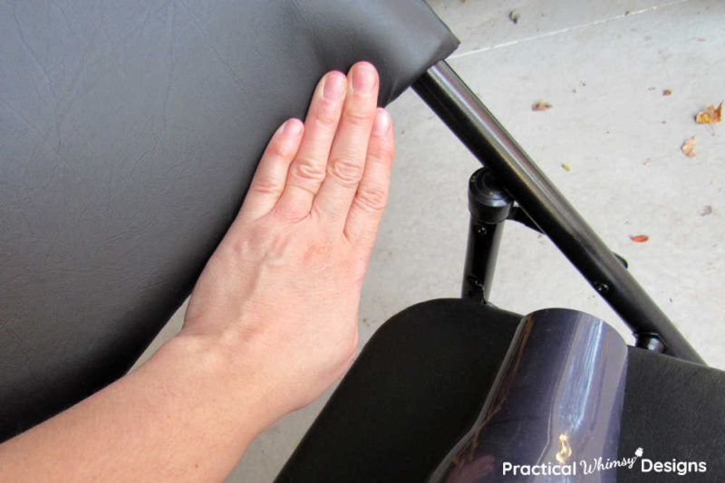 Hand smoothing vinyl on black vinyl folding chair.