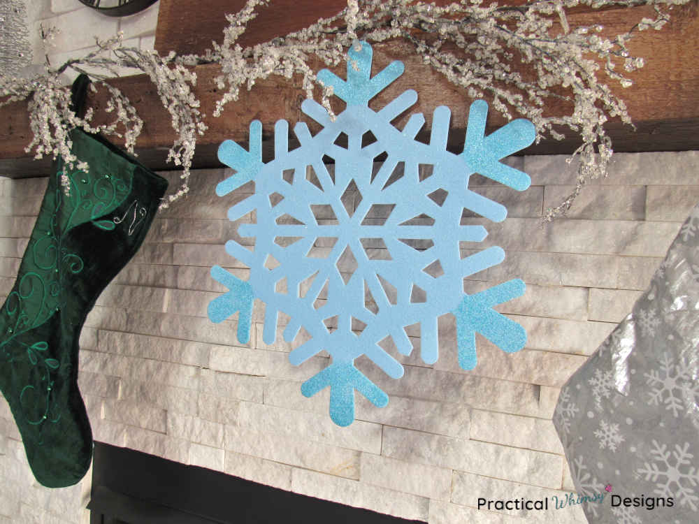 Blue snowflake and stockings hanging on mantel.