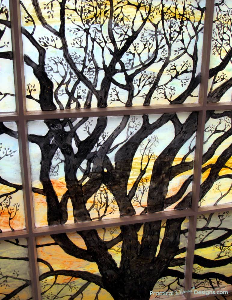 Stained glass art tree silhouette with light shining behind it.