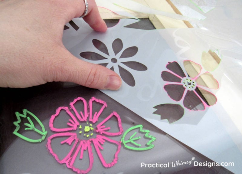 Hand holding flower stencil onto faux chalkboard