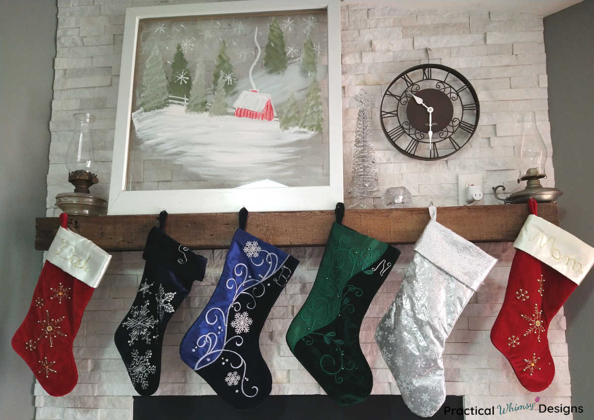Stockings hanging on mantel below snowy barn picture