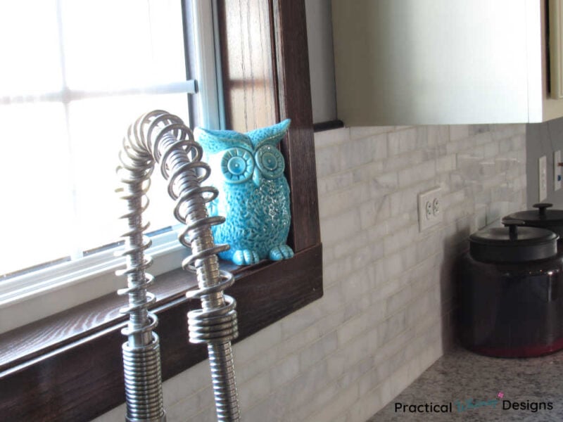 Teal towel sitting on window trim in kitchen