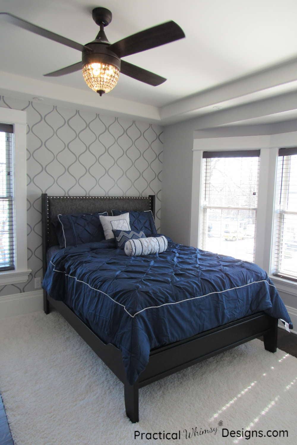 Master bed with navy comforter and gray stenciled accent wall in master bedroom.