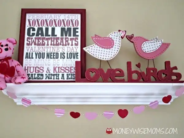 Valentine's display on white shelf with paper heart garland on front.
