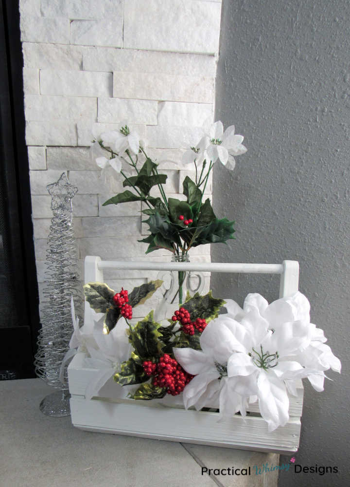 White wooden caddy filled with white and red Christmas flowers.