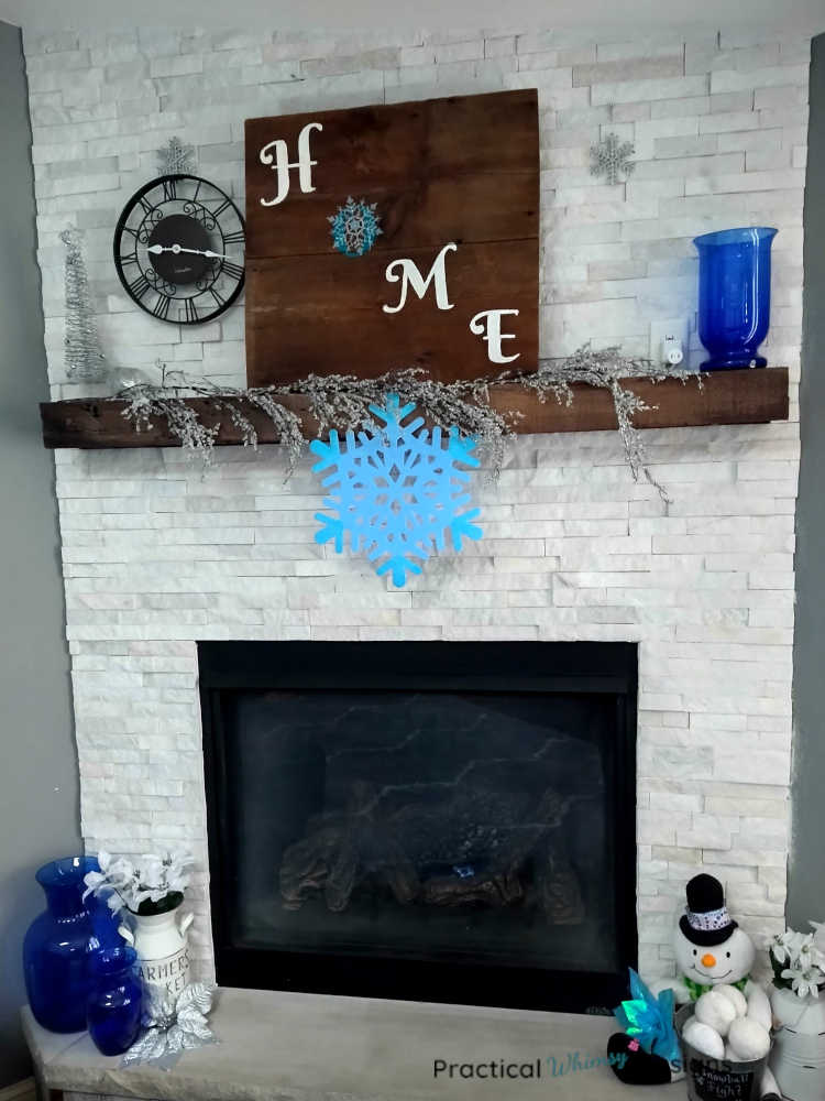 Winter mantel decor with snowflakes, silver tree, and blue vase