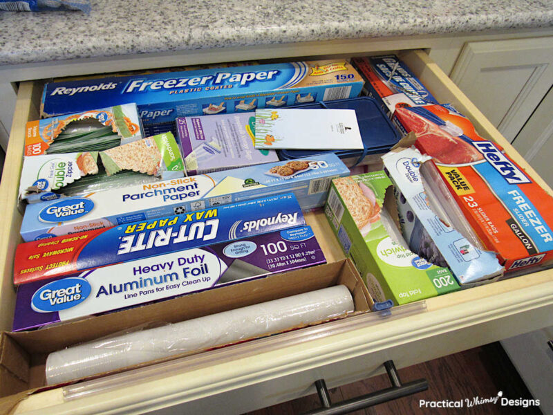 Plastic ziploc bags, saran wrap, tin foil, and paper products in a kitchen drawer.