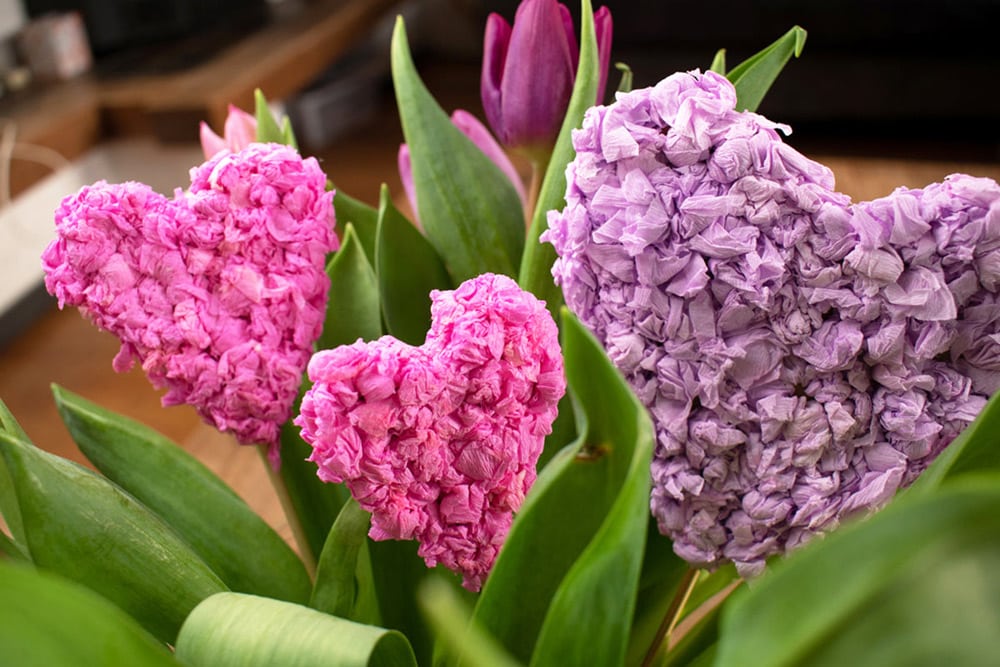 Pink and purple tissue paper hearts in a vase of tulips.