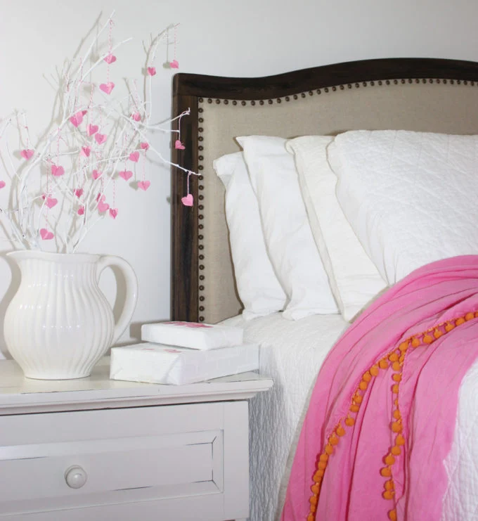 Heart leaf branches in white pitcher by bed
